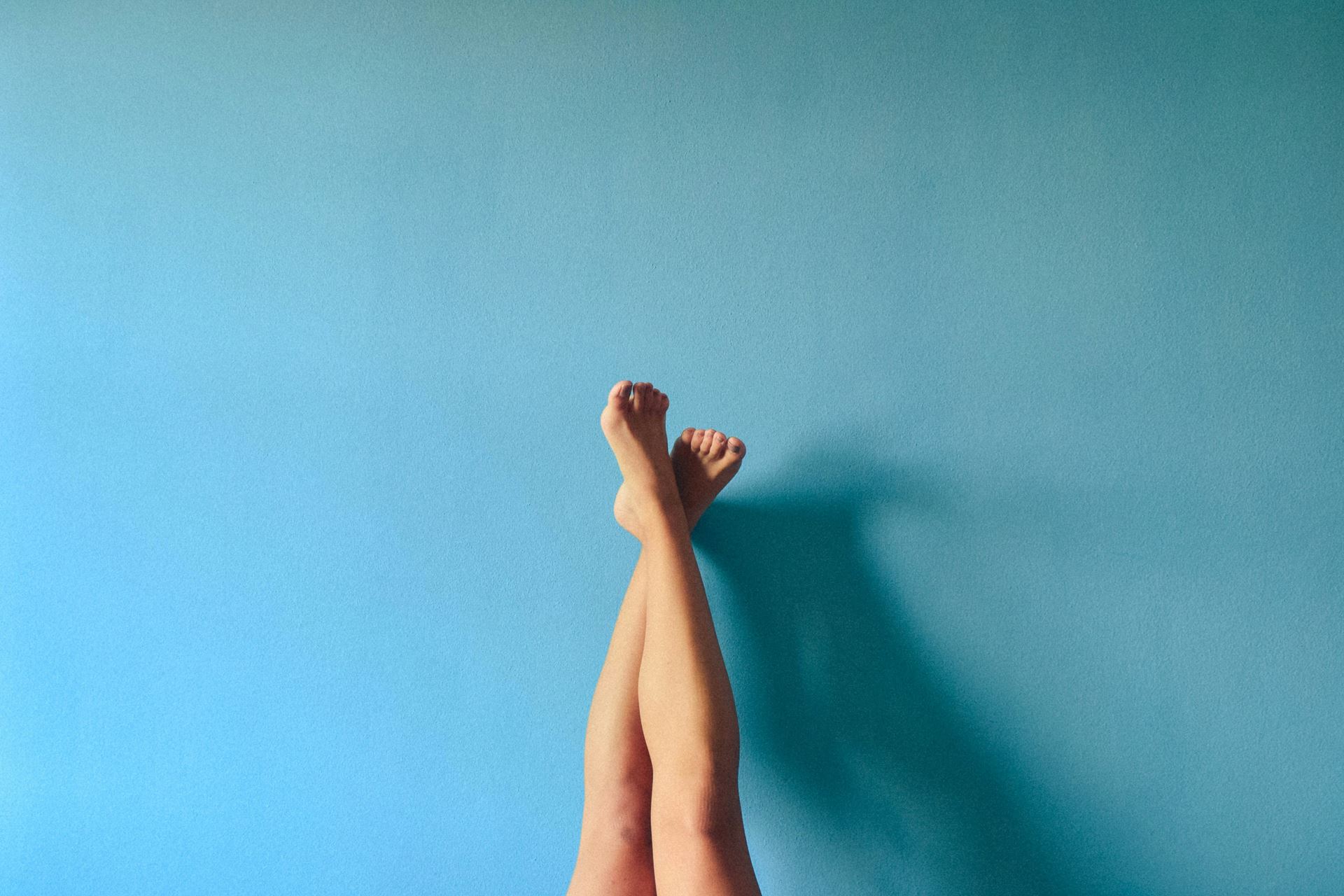 Legs and feet against a blue wall